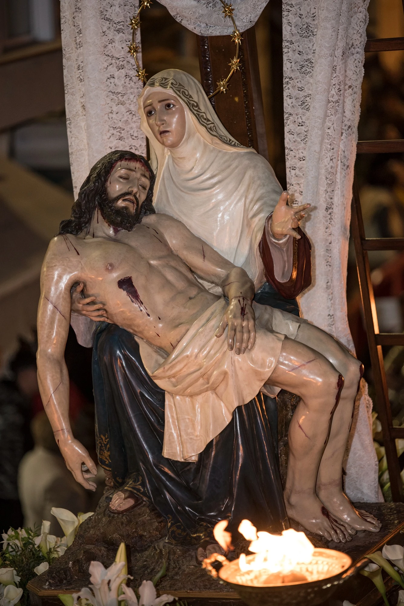 Vista cercana de la Virgen de las Angustias con Cristo en su regazo y una llama en primer plano