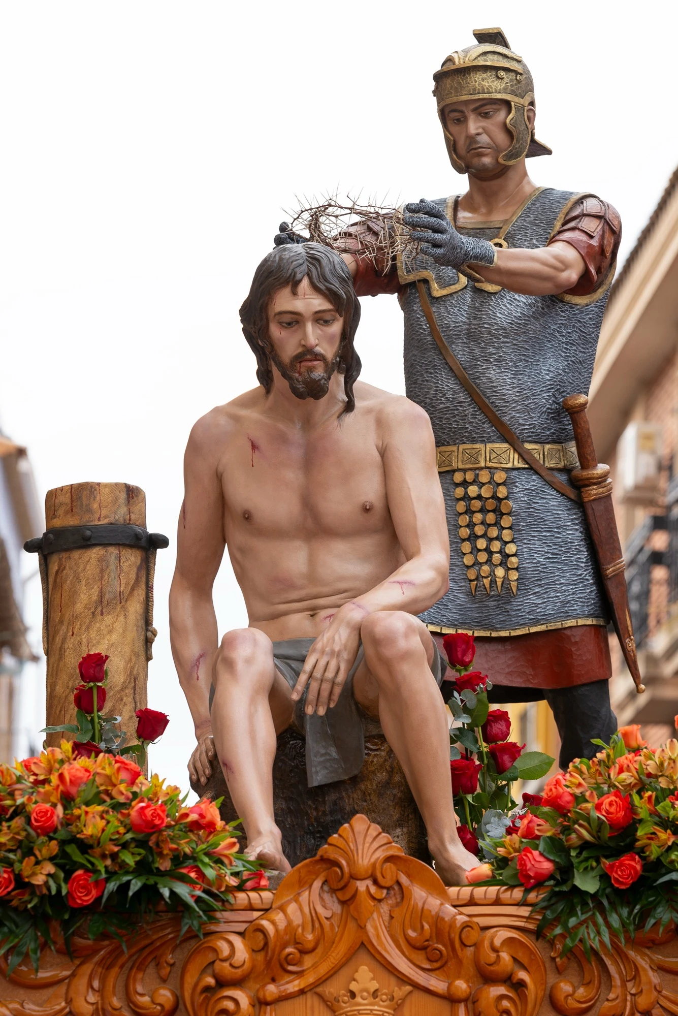 Cristo sentado y el soldado con la corona de espinas sobre el trono adornado con flores